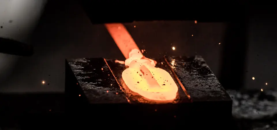 Pièce en acier estampée à chaud, encore incandescente sur la matrice