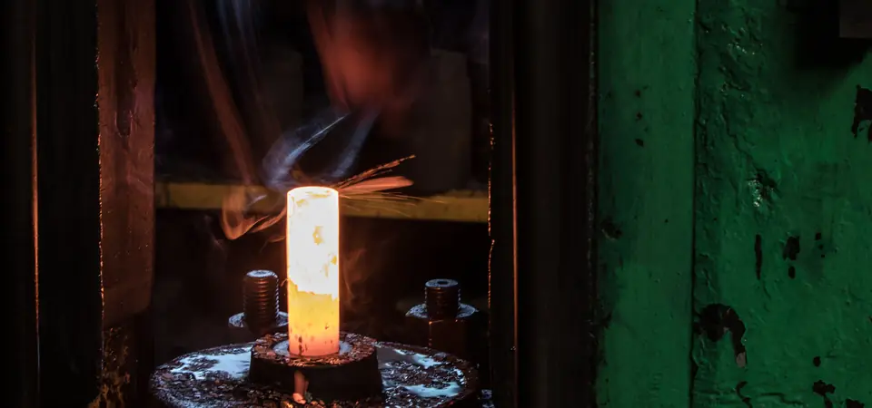 Lopin d'acier incandescent sous la presse dans l'atelier de forge